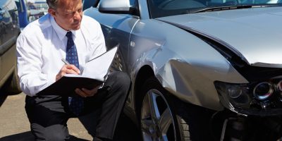 Loss Adjuster Inspecting Car Involved In Accident